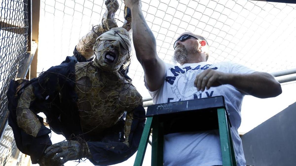 
Volunteer Brent Curtis of Kennewick works on hanging a mummy at the Project 13 haunted house at the Benton County Fairgrounds in Kennewick. The mad-scientist themed house is one of three haunted houses opening Oct. 2 as part of “Scaregrounds.”
