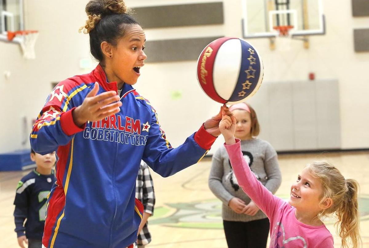 Briana “Hoops” Green, a Harlem Globetrotters player, helps Bristol Wilson spin the basketball on her fingertip during a previous visit to the YMCA of the Greater Tri-Cities.