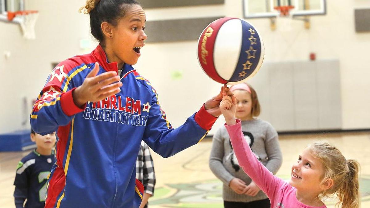 Briana “Hoops” Green, a Harlem Globetrotters player, helps Bristol Wilson, 5, spin the basketball on her fingertip during a recent visit to the YMCA of the Greater Tri-Cities before- and after-school program at Sage Crest Elementary School in Kennewick. Watch a video at: tricityherald.com/video