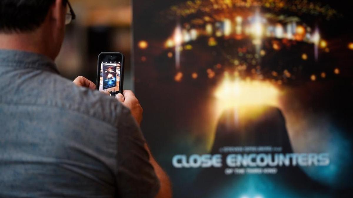 A filmgoer takes a picture of the poster for “Close Encounters of the Third Kind” before a 40th Anniversary screening of the film at the Cinerama Dome on Wednesday, Aug. 30, 2017, in Los Angeles. UFO enthusiasts are being drawn to a strange geological formation in Wyoming, similar to one depicted in the 1977 film.