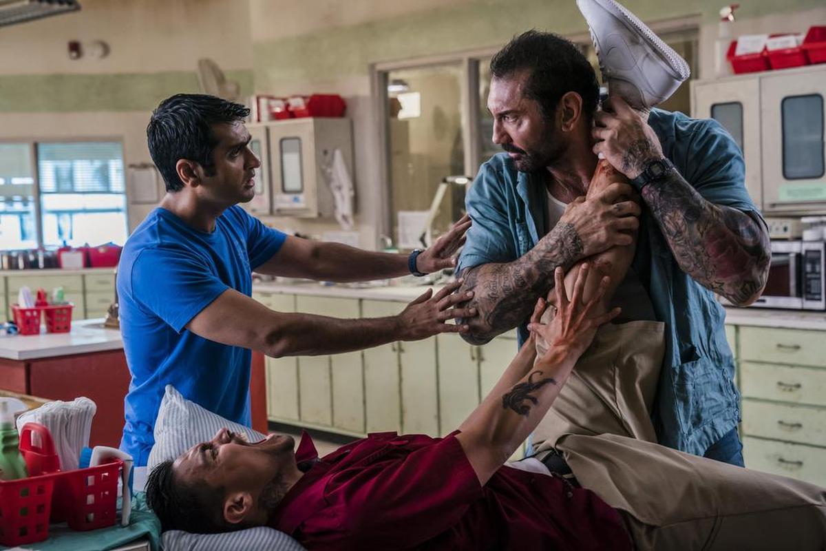 This image released by 20th Century Fox shows Dave Bautista, right, and Kumail Nanjiani, standing left, in a scene from "Stuber."