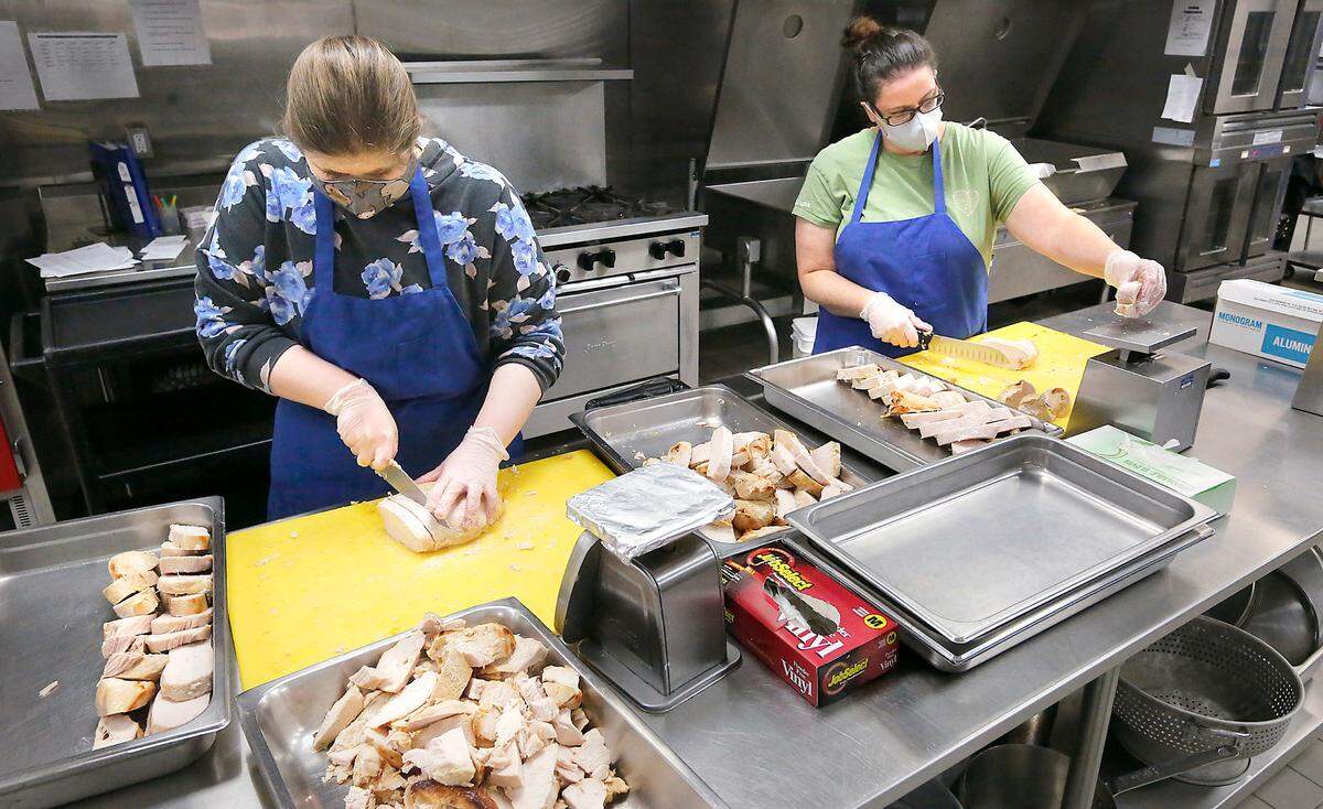 Kitchen staff members Jessica Clift, left, and Carrie Myers work together Tuesday morning slicing 78 cooked turkey breasts for the traditional Thanksgiving meal to be delivered or handed out Nov. 25 by the Mid-Columbia Meals on Wheels program.