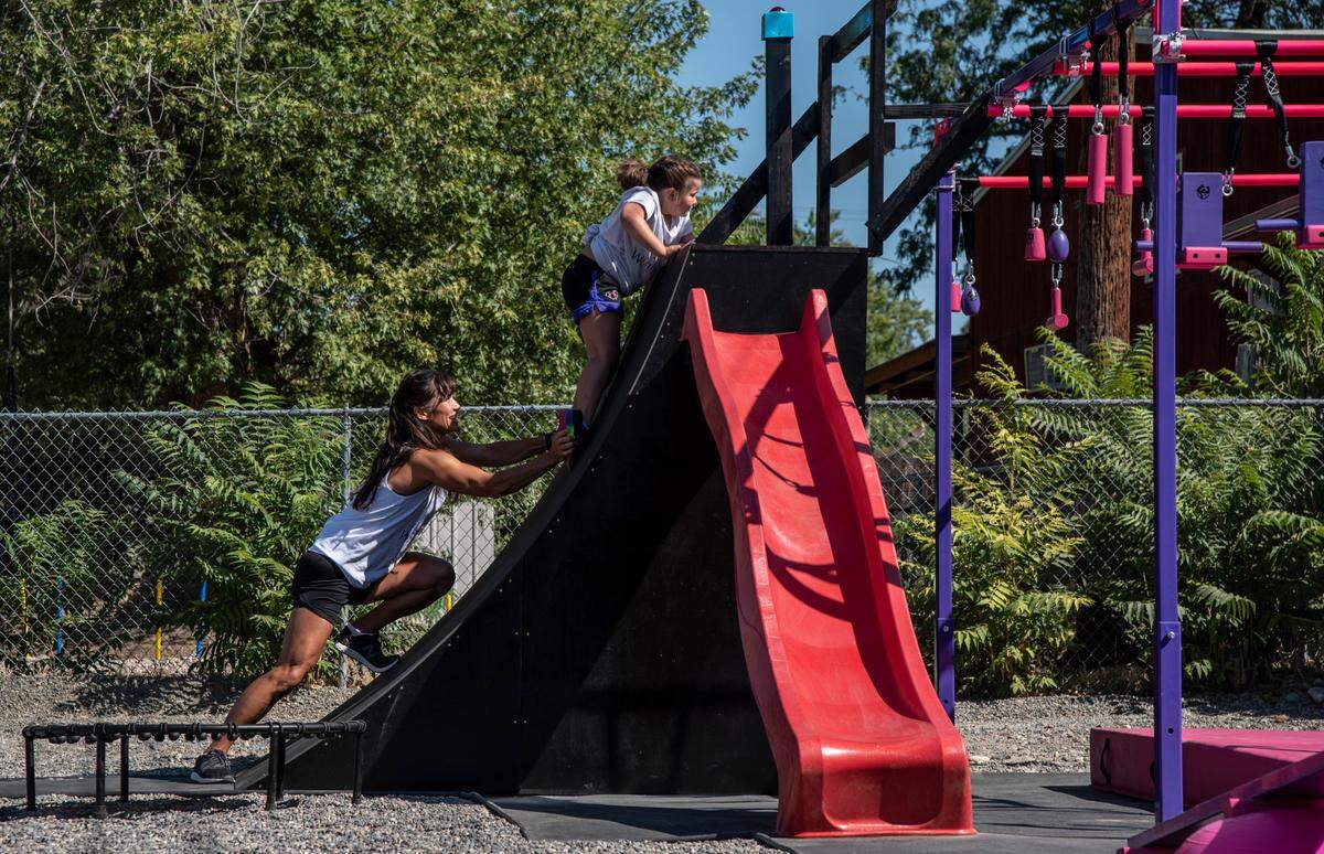 Oaklee McBride, 5, gets a little boost on her new backyard obstacle course from Sandy Zimmerman, a record-setting competitor from Oaklee’s favorite show, American Ninja Warrior.