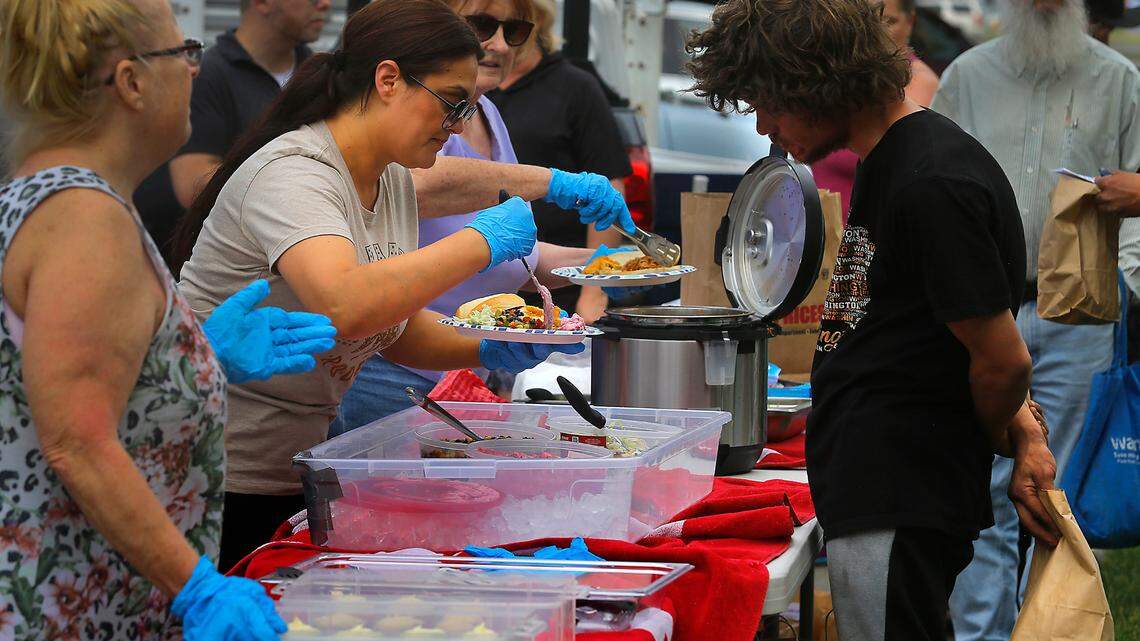 Volunteers fixes sandwiches for others during a weekly free meal in Kennewick’s Keewaydin Park for people experiencing homelessness.