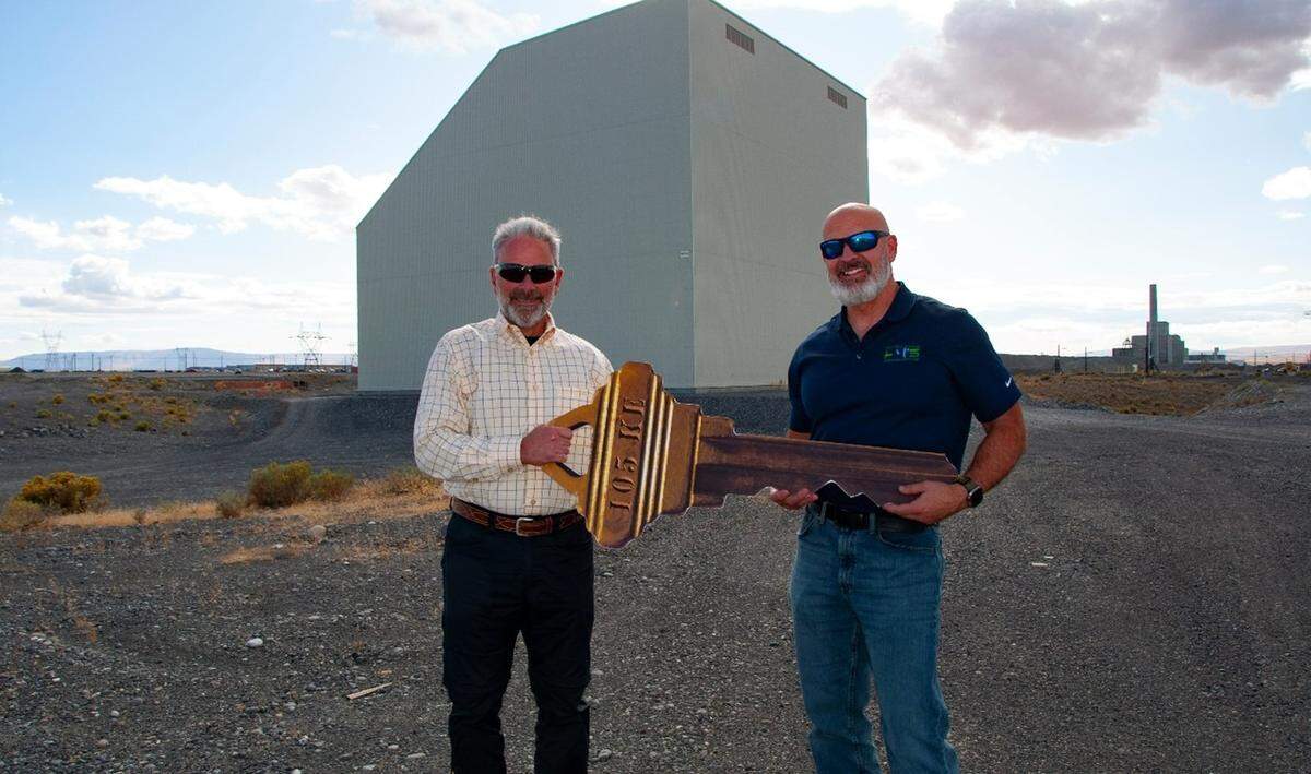 John Eschenberg, president of Central Plateau Cleanup Co., gives a symbolic key for management of the K East Reactor at Hanford to Bob Wilkinson, president of Hanford Mission Integration Solutions in 2022.
