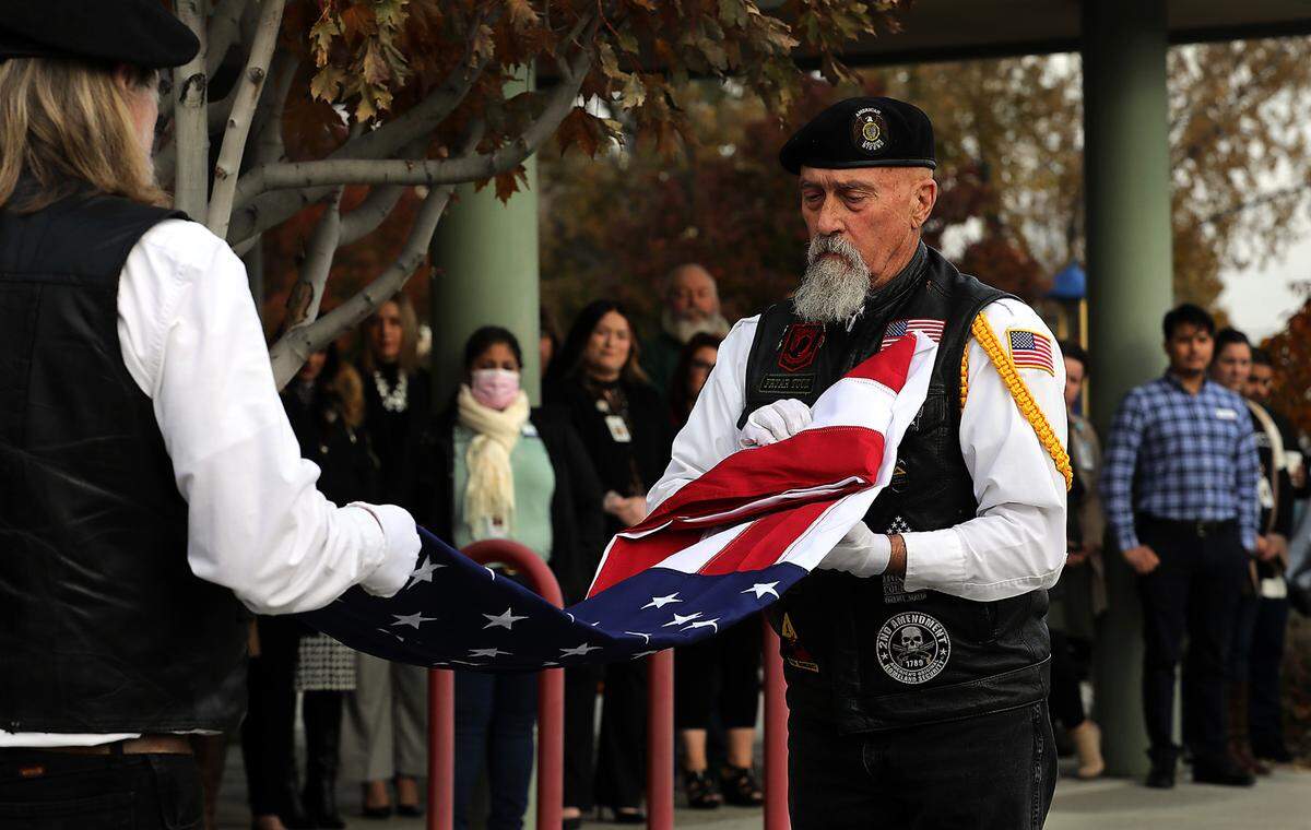 Don Houlihan, left, and Chris Tucker, both Honor Guard members of the Glenn M. Sickles Post 34 of Kennewick & Pasco American Legion, unfold a new U.S. Flag during a Veterans Day Flag Raising ceremony in Richland.