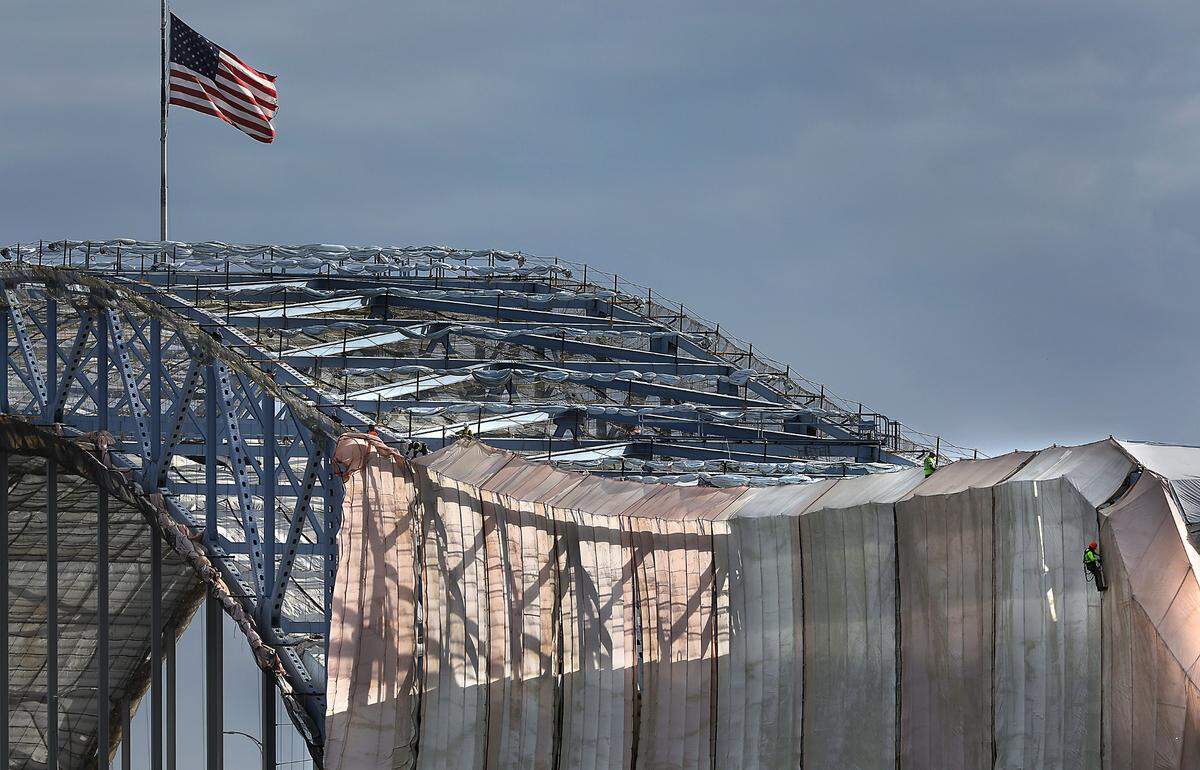 Construction workers climb on the girders taking down the “cocoon” of tarps on the south side of the Highway 395 blue bridge over the Columbia River.