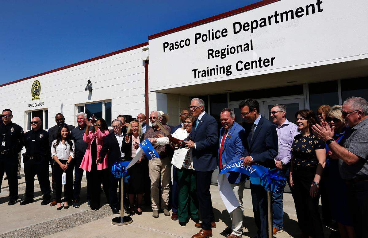Washington Gov. Jay Inslee is surrounded by community members, law enforcement officials and elected official for the ribbon cutting ceremony in Pasco.