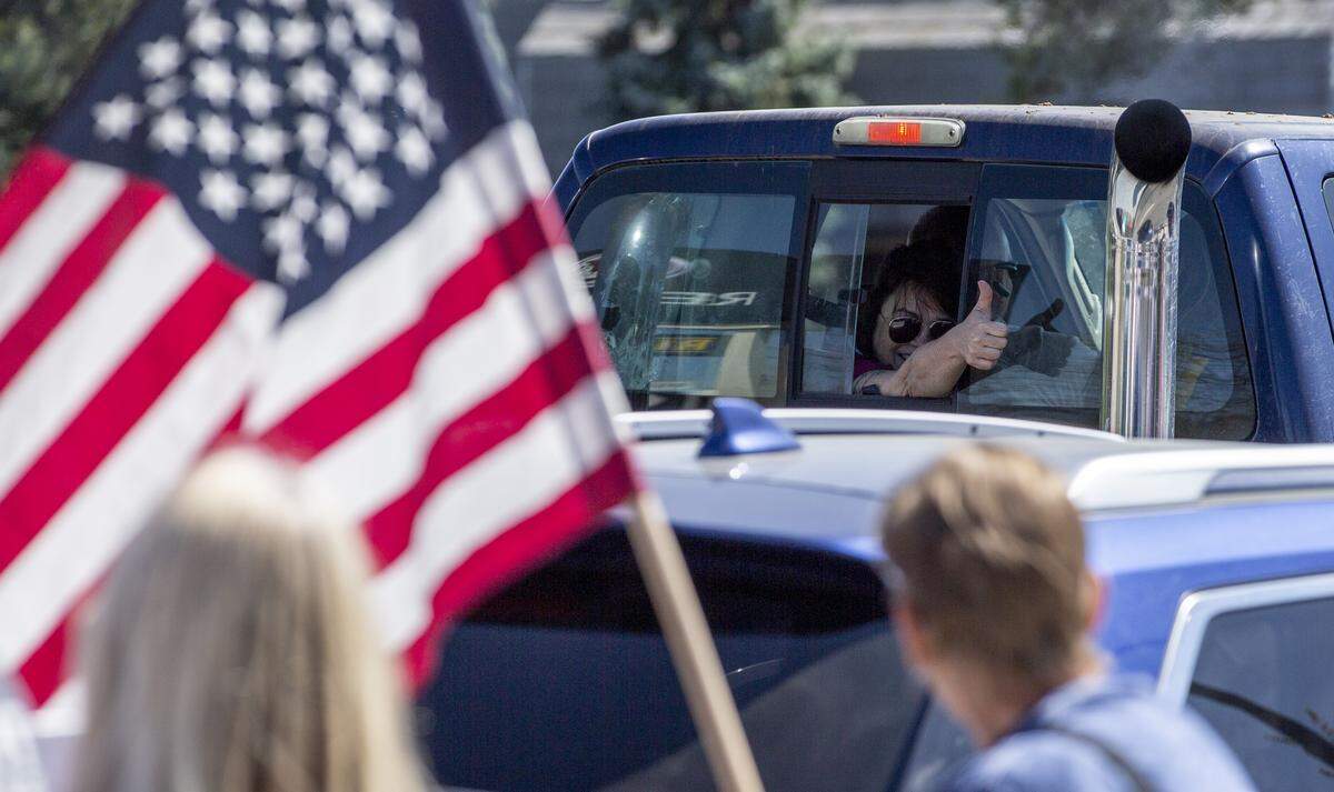 More than 100 protesters lined sidewalks on George Washington Way in Richland on Sunday to wave American flags and signs, angry over Gov. Jay Inslee’s stay home order to slow the coronavirus and COVID-19.