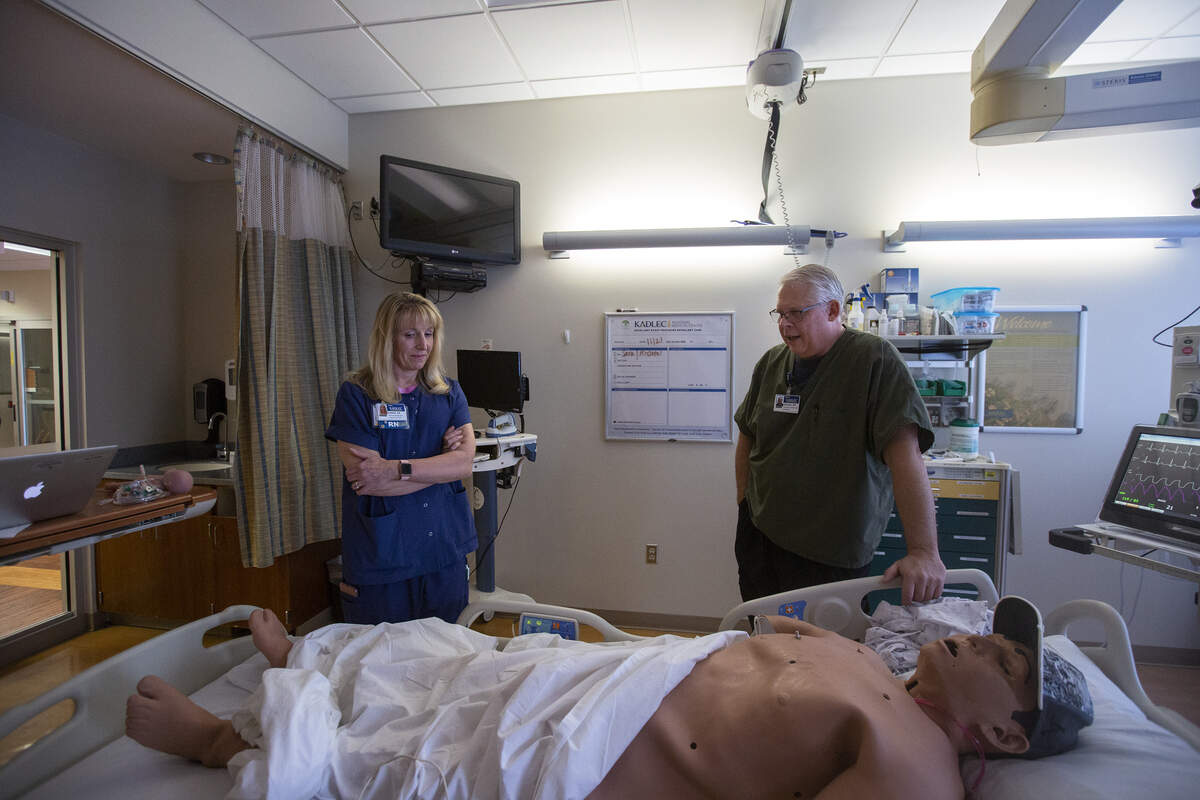 Clinical educator Donna Osborne, left, and Mike Anderson, who runs the lab, stand inside the simulation room that looks the same as the hospital room employees would be working in. The human-like piece of equipment is used to help Kadlec Regional Medical Center employees prepare and practice for real patients.