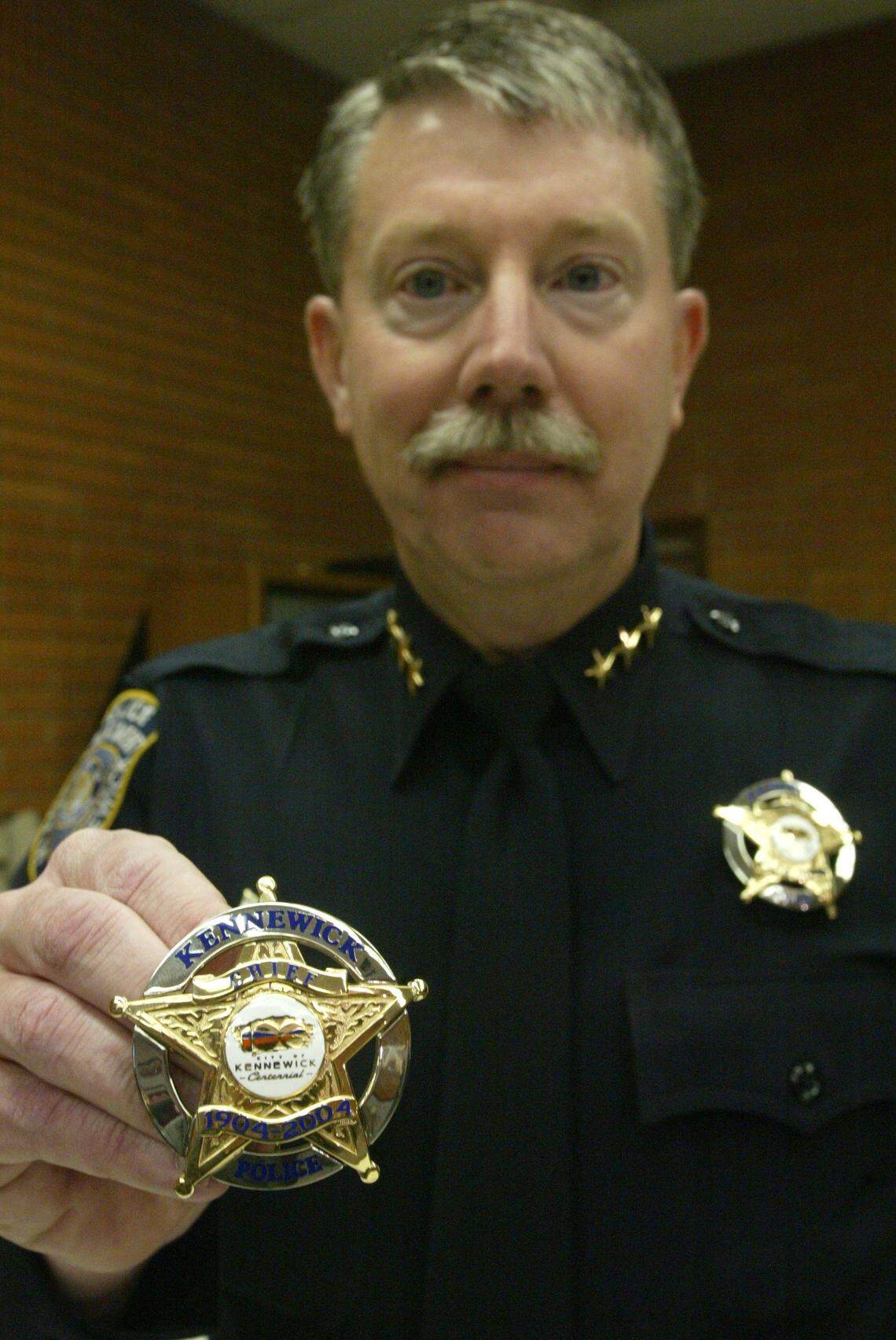 Kennewick Police Chief Ken Hohenberg shows one of the centennial police badges in 2004 some of his officers wore to celebrate the city's 100th birthday.