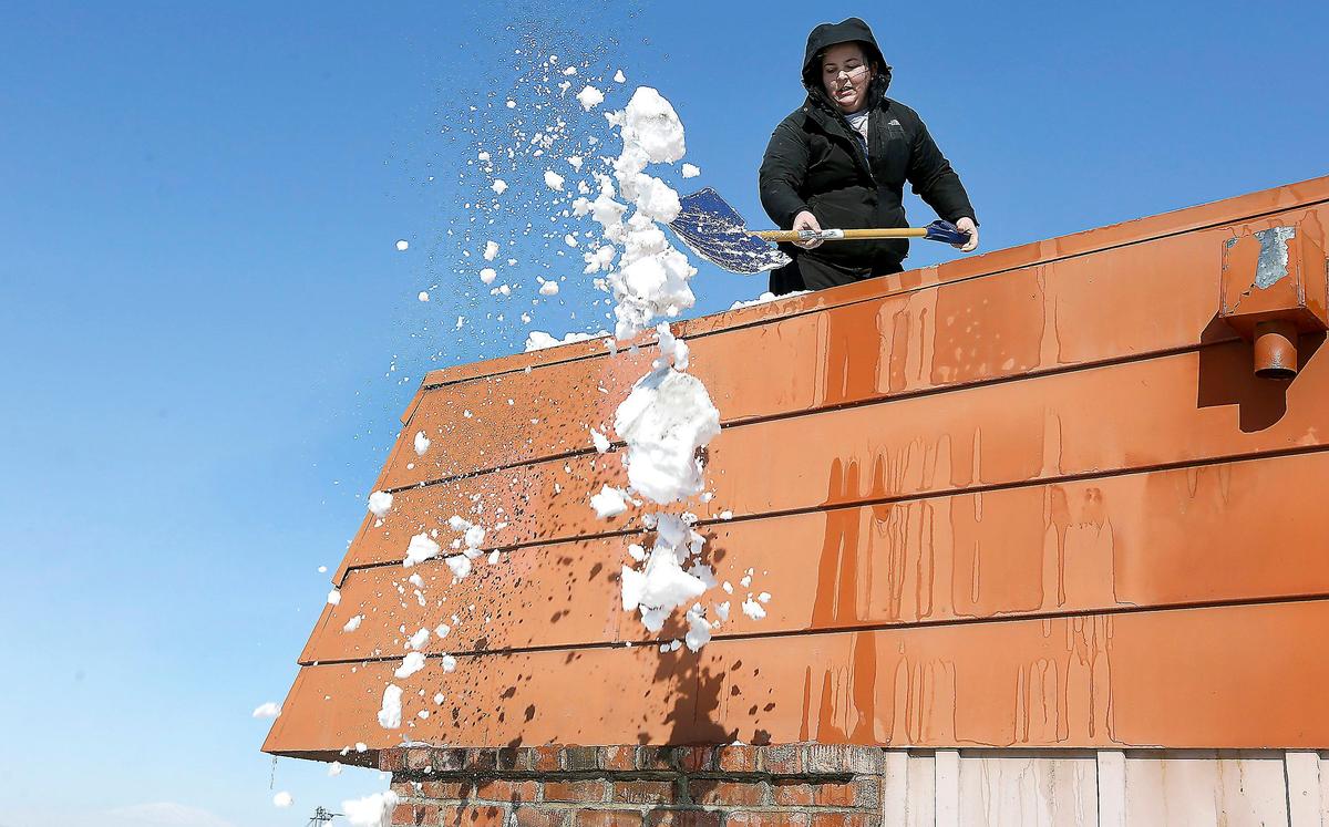 Abbey Prunier, an employee of Columbia Valley Chiropractic Center, uses a shovel to remove snow from the roof of the building Thursday at Tapteal Loop and West Yellowstone Avenue in Richland.