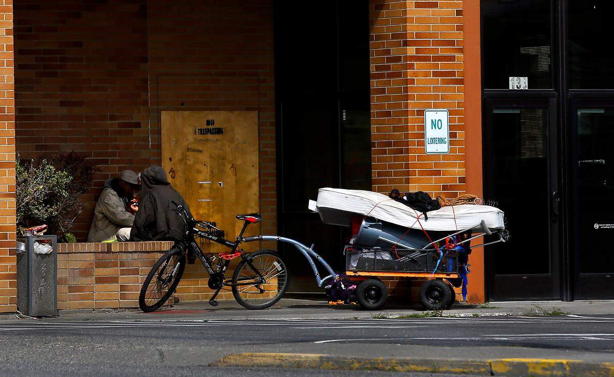 A pair of homeless men sit with their belongings in the entryway of a vacant building on Vista Way in Kennewick in early 2023.