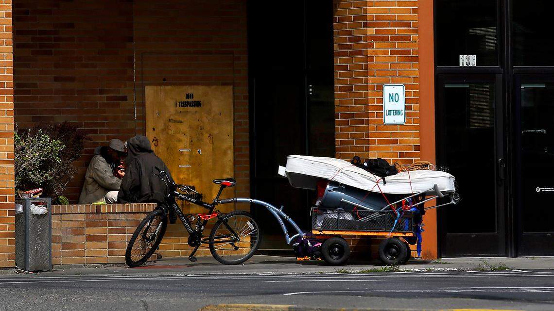 A pair of apparently homeless men sit with their belongings in the entryway of a vacant building on Vista Way in Kennewick in early 2023.