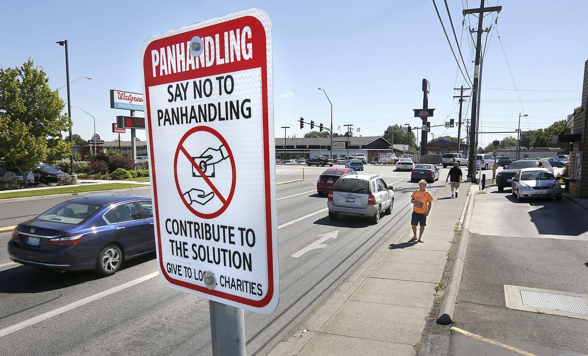 Chris McEachern, 47, asks drivers for money at West Clearwater Avenue and Highway 395 on Tuesday near a new sign installed by Kennewick urging motorists to contribute to local charities instead of panhandlers. "I won't change .... as long as people don't get mad at me about it.," said McEachern. Watch a video at: tricityherald.com/video