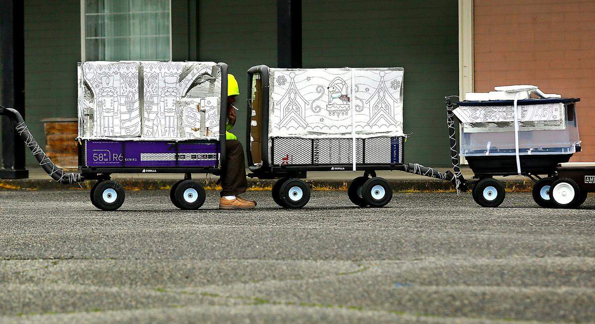 An apparently homeless man smokes while sitting in the back of a covered wagon train in the parking lot of a vacant retail store in Richland on Jadwin Avenue on April 10, 2023