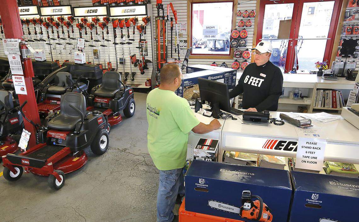 Keith Silliman, owner of Farmers Exchange in Kennewick, helps customer Brandon Ortiz, owner of Integrity Lawn Care, with a purchase from behind a blocked off sales counter. Silliman printed social distancing T-shirts and posted signs, marked floors and is limiting the number of people in the buildings at one time. Watch a video at: tricityherald.com/videos