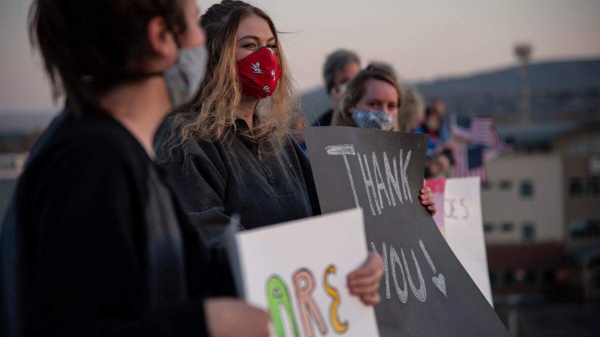 Allison Taton, 18, second from left, holds a sign to show support for hospital staff at Kadlec Regional Medical Center in Richland. The Kennewick teen helped organize a gathering on the roof of the parking garage to show support for health care workers.