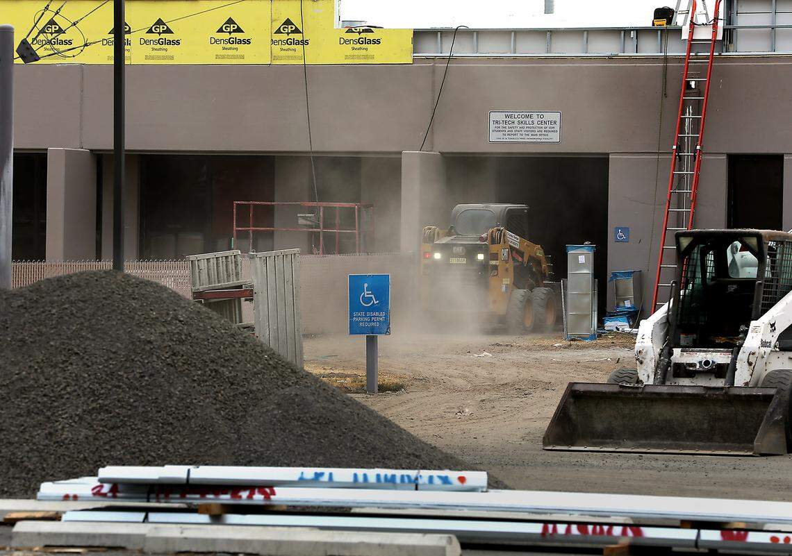 Construction equipment kicks up a cloud of dust while hauling a load of gravel to inside the Tri-Tech Skills Center building.