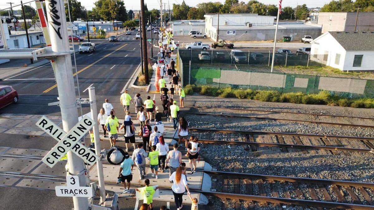 Participants march through Kennewick to line up across the cable bridge during the 2023 Hands Across the Bridge Tri-Cities overdose awareness event.