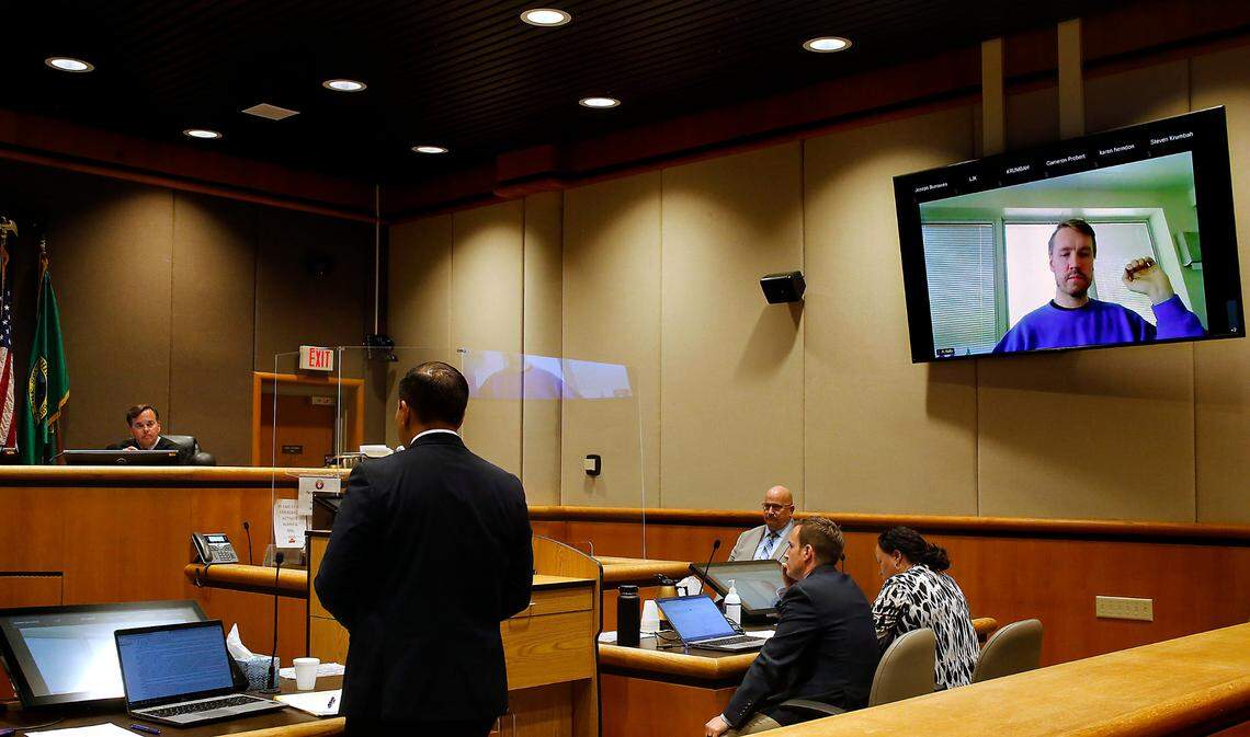Aaron Kelly, who is accused of shooting two men inside the Richland Fred Meyer store in February 2022, raises his hand during a court hearing in Benton County Superior Court in Kennewick.