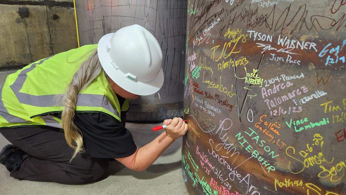 Candice Robertson, Department of Energy senior adviser for environmental management, adds her signature to the first container of test glass that was poured and filled in November 2023 at the Hanford vitrification plant.