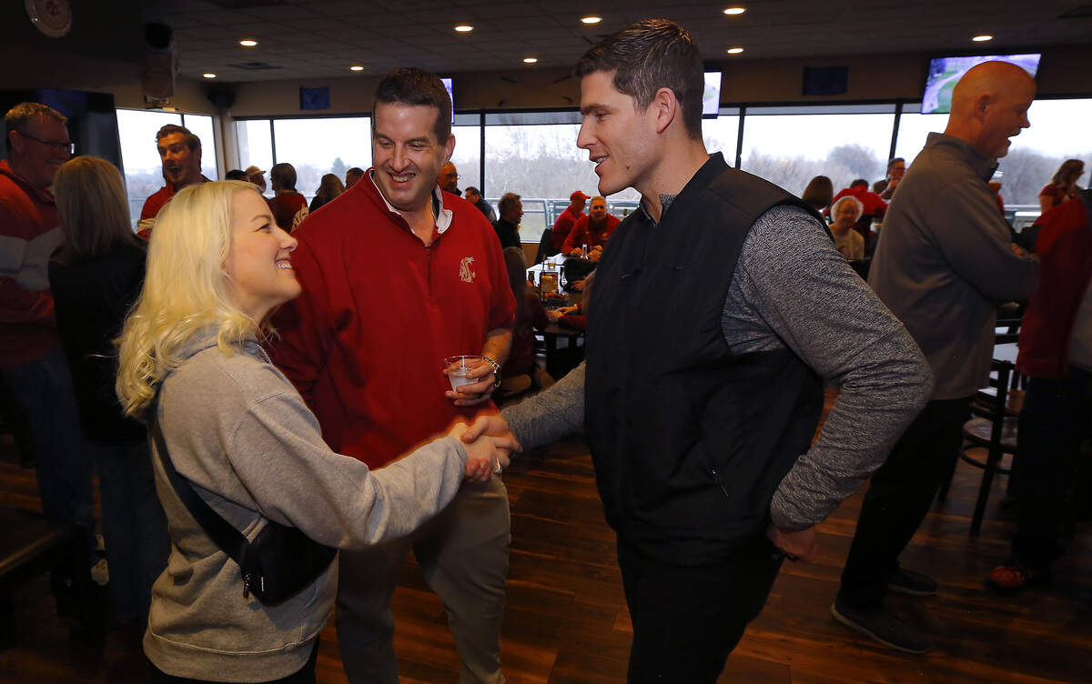 Prosser High graduate Kirby Moore, the new 36th Washington State University head football coach, shakes hands with Sara Cochran of Richland during a "meet and greet" event held by the Cougar Athletic Fund at Zintel Creek Golf Course in Kennewick. Cochran's brother, Scott Silva of Richland, stands next to them.