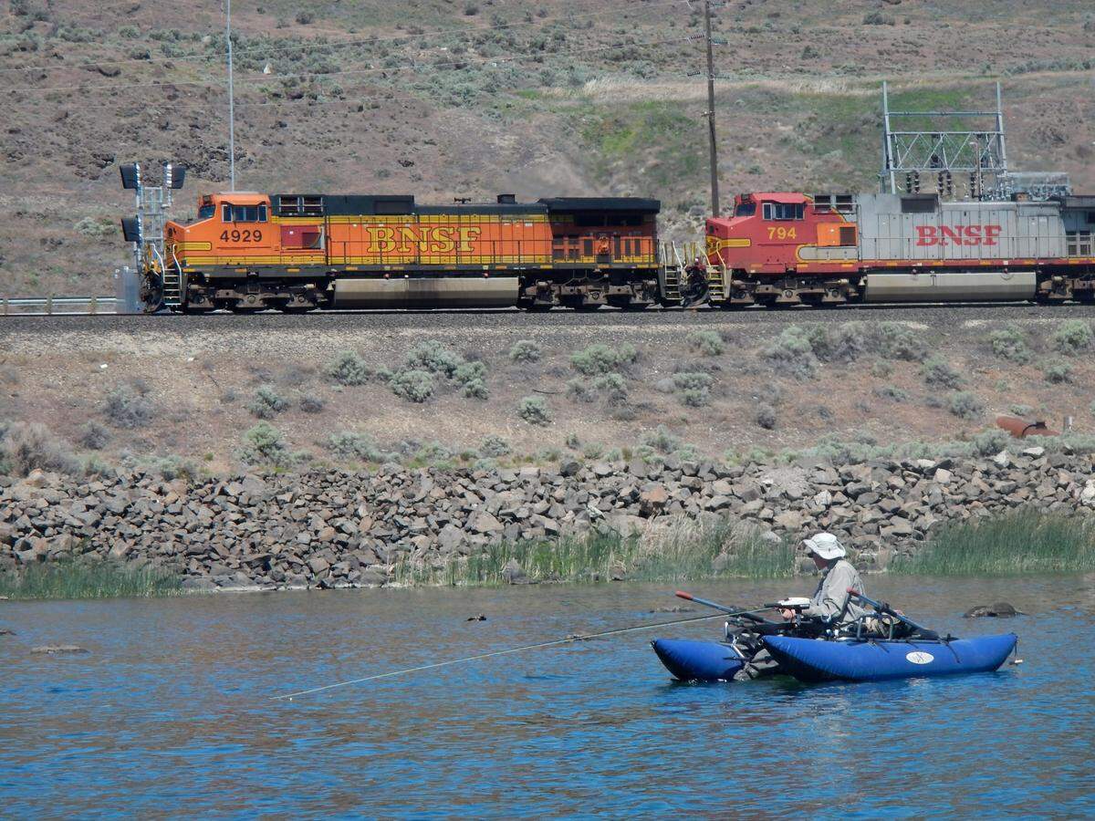 A westbound coal train is backdrop to a pontoon boat angler trying for smallmouth bass near Crow Butte State Park.