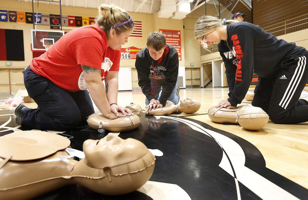 Katie Busch, left, an EMT with American Medical Response, helps River View High sophomore Andrew Miles and Gracie Boyd practice a compression-only technique during a CPR challenge event at the school in Finley in 2019.