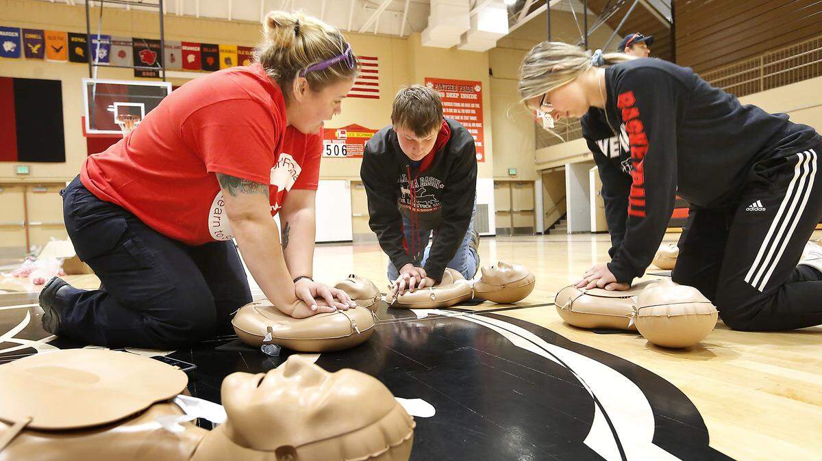 Katie Busch, left, an EMT with American Medical Response, helps River View High sophomore Andrew Miles and Gracie Boyd practice a compression-only technique during a CPR challenge event at the school in Finley in 2019. The event was held in conjunction with National Emergency Services Week.