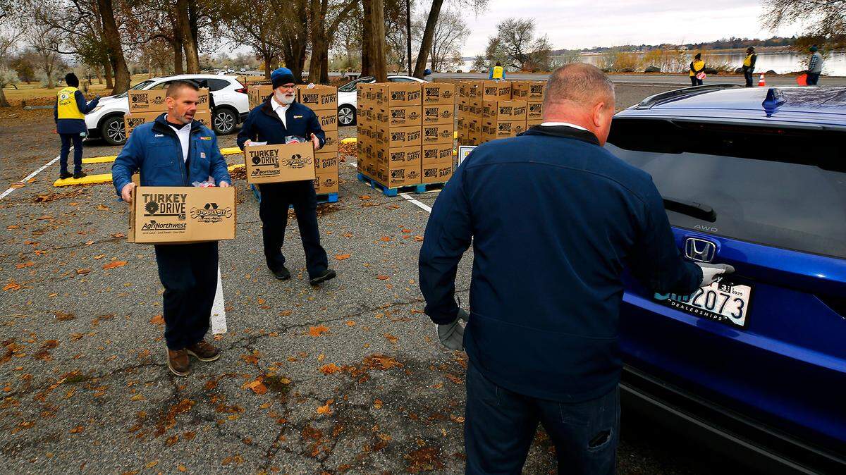 Les Schwab Tires employees Heath Schilz, Bart Hill and Matt Onstatt, from left, volunteer loading vehicles at Tuesday’s 2nd Harvest Turkey Drive turkey dinner distribution. Tri-City families pre-registered for the event to receive 230 complete meals.