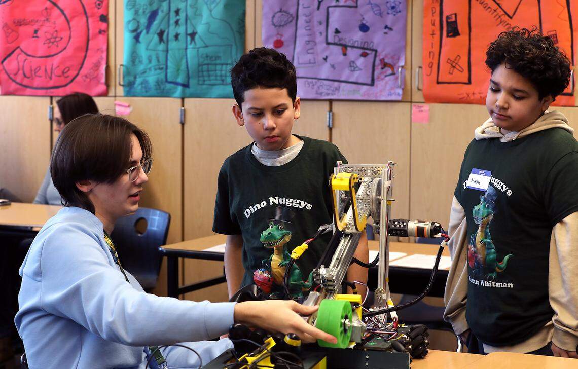 Tyler Bartlett, a Richland High School senior, demonstrates a robot he helped build to Sergio Preciado, left, and Nash Ramirez.