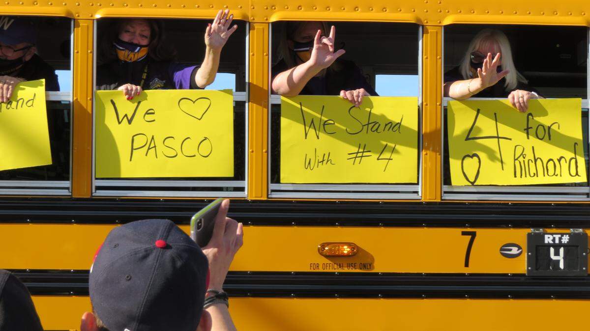 People inside of a school bus hold signs remembering Dick Lenhart as part of Saturday’s bus parade in memory of a slain Pasco school bus driver.