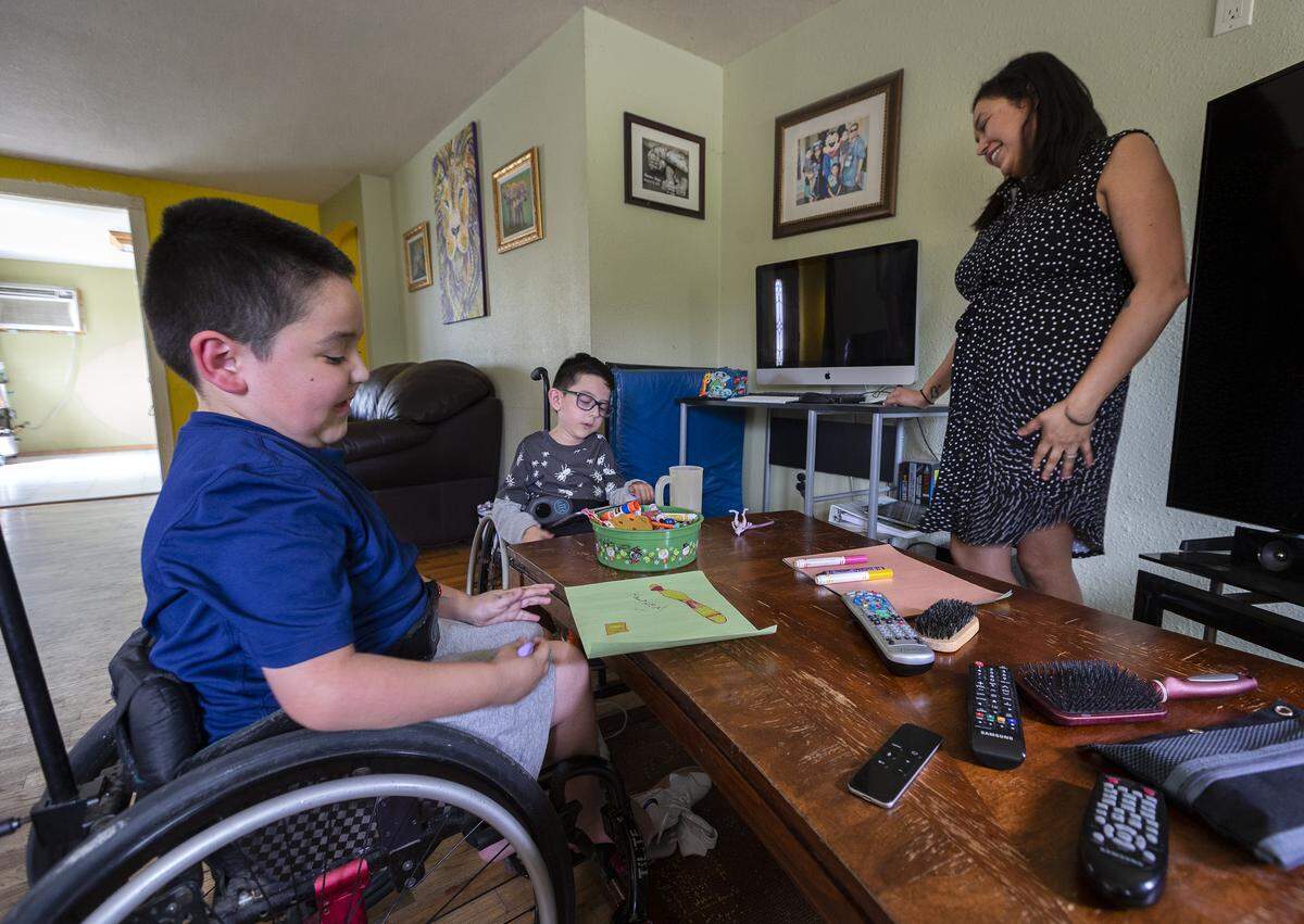Crystal Ramos, right, smiles while talking with her twin boys Hendrix, center, and Harper inside their home in Pasco. Ramos says they are happy, energetic boys who are full of life.