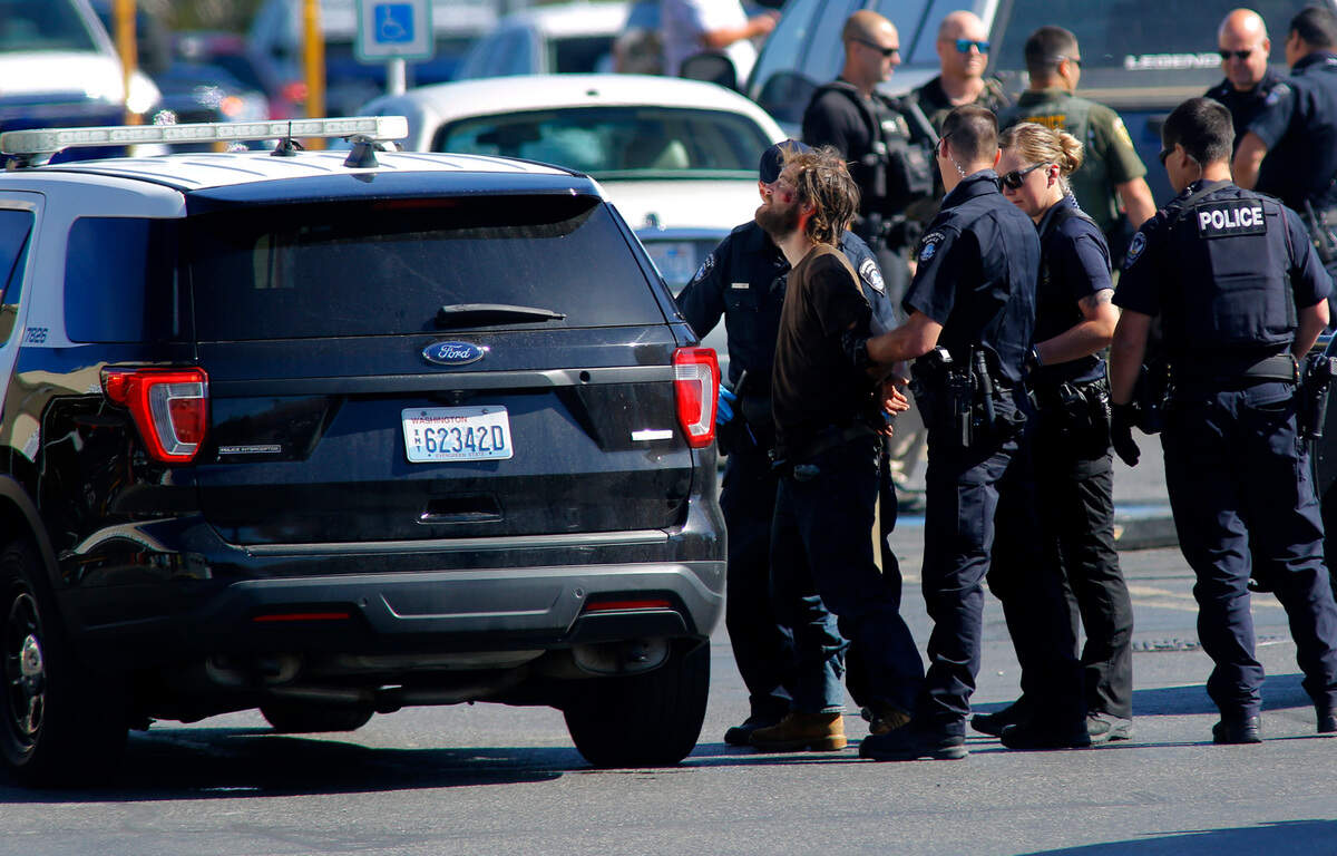 Kerry Brooks, 28, is placed in a patrol vehicle by police officers Wednesday morning in the parking lot of Ranch & Home store on Columbia Center Boulevard in Kennewick. Police say Brooks entered the store brandishing the knife demanding employees sell him a firearm. The employees were able to get Brooks outside the business and lock the doors while calling police. Officers negotiated with him for about an hour before using a non-lethal round to knock the knife from his hand, set off a noise making device as a distraction and then swarm him to safely take him into custody.