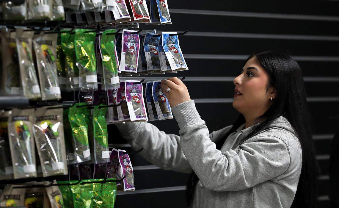 Employee Andrea Santillan sets up the displays at the new Lucky Leaf Co. cannabis store.
