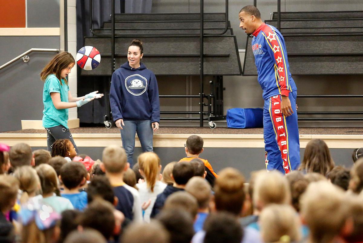 Fourth-grader Stefani Patko passes the basketball to Harlem Globetrotter Julian “Zeus” McClurkin by bouncing it off her head during Friday’s anti-bullying assembly at Amon Creek Elementary School. Teacher Jamie Whitmire watches. Watch a video at: tricityherald.com/videos