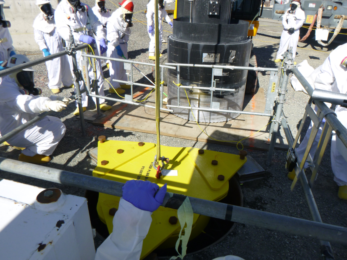 Hanford nuclear site crews connect a pipe to the top of an underground waste tank, A-106, foreground, after removing a thick concrete core from the tank dome using a large drill, background, to provide access for installing waste retrieval equipment.
