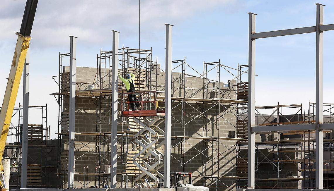 A construction worker takes a measurement while working from a lift installing steel support beams for the $10 million expansion at the Tri-Tech Skills Center in Kennewick in 2020.