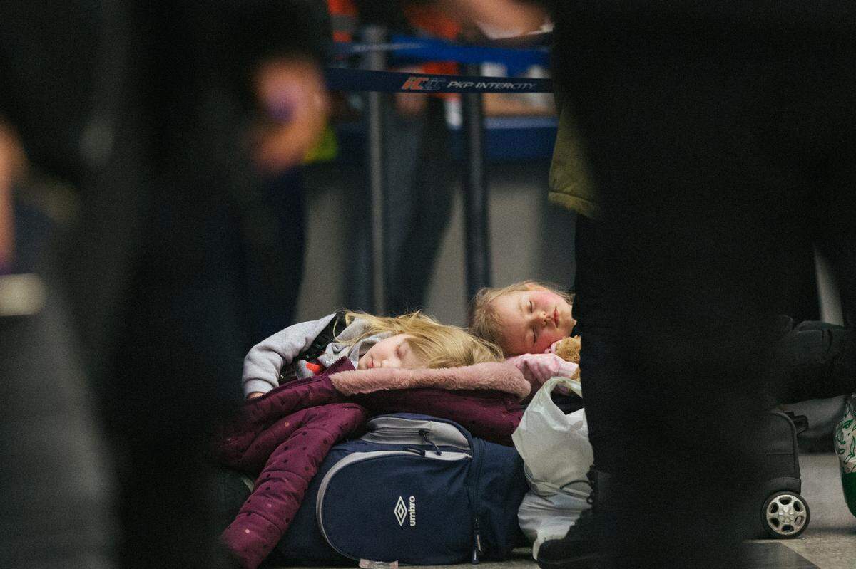 Ukrainian children sleep on luggage, in a Krakow, Poland, train station on the evening of March 9 after traveling all day. Nearly 4 million have fled the country since Russia began a large-scale military assault.