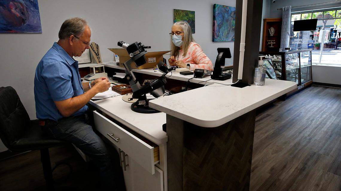 Dennis Schoeneberg of Desert Gem & Appraisal helps customer Lorna Streichen of Kennewick in the downtown Kennewick business that recently reopened after a devastating fire gutted the adjacent Cascade Building in February.