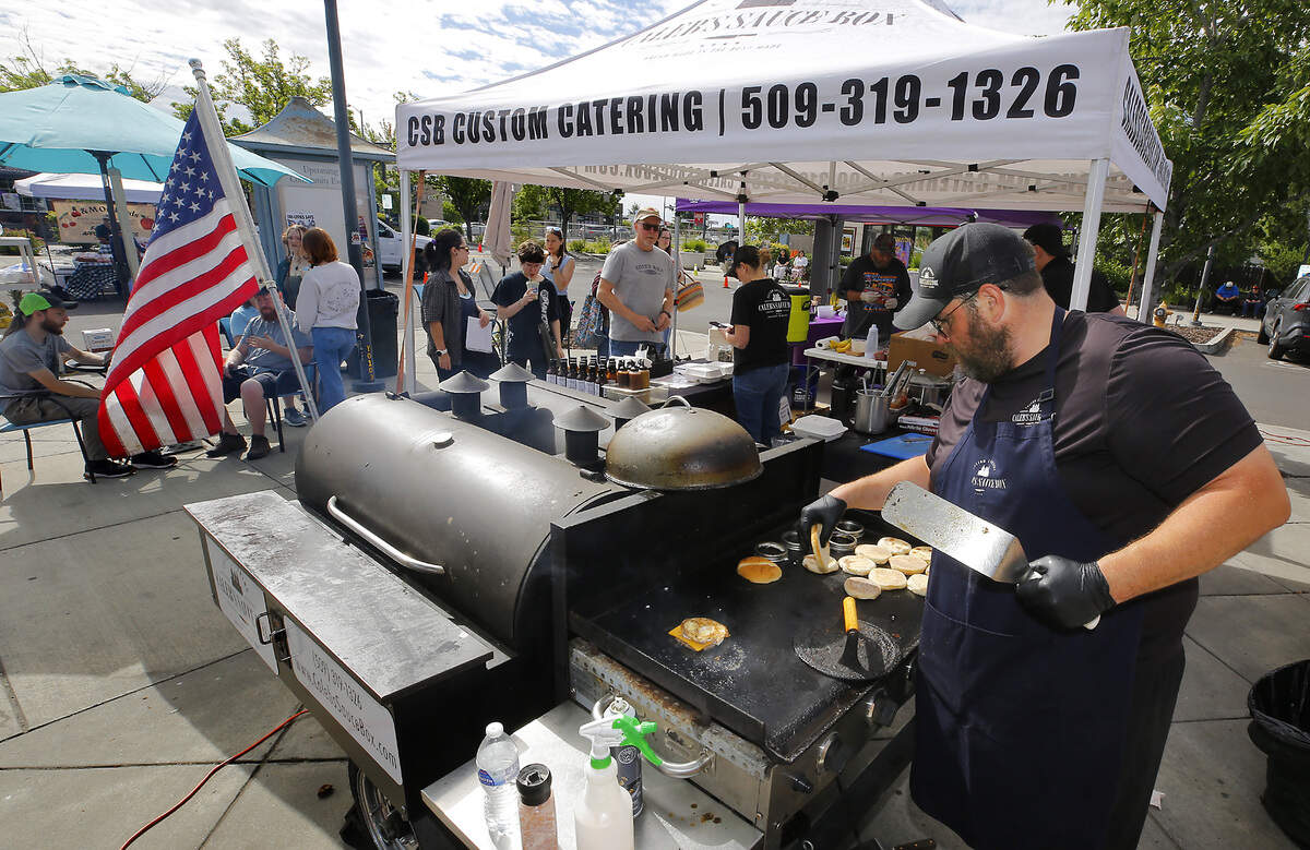 Caleb Ashbeck, owner of Caleb's Sauce Box, cooks sausage breakfast sandwiches on his mobile smoker and griddle trailer Friday morning for the opening day of the Richland Farmers Market. He's starting his fourth year at the seasonal market and has a loyal customer base for his barbecue sauces and sandwiches.