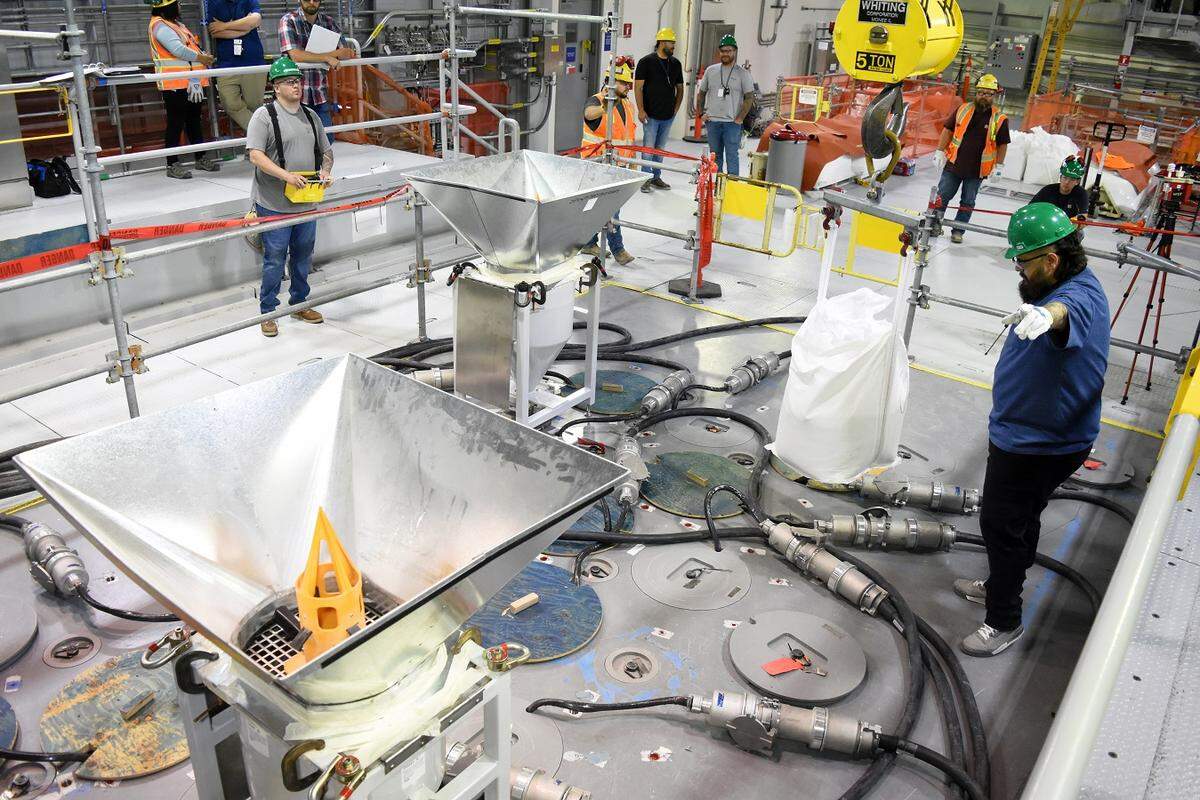 Workers at the Hanford site vitrification plant add frit, or glass beads, to the melter inside the Low-Activity Waste Facility.