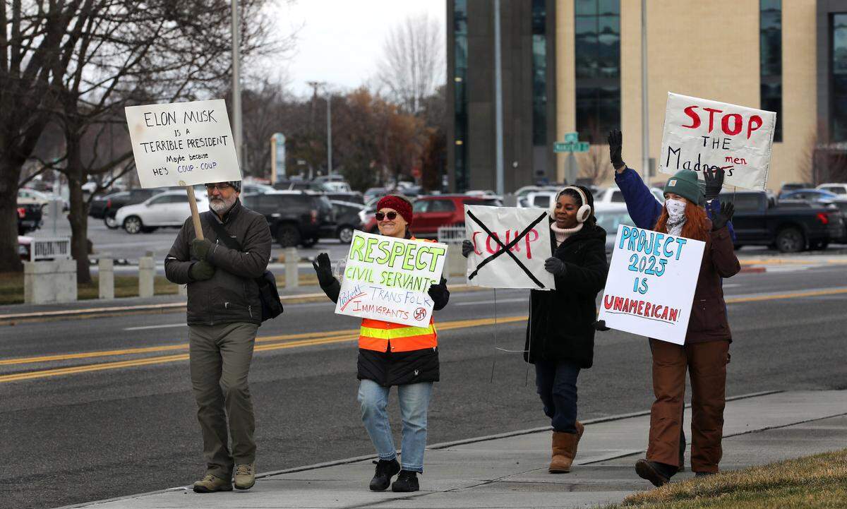 Demonstrators hold signs Wednesday afternoon while walking on Jadwin Avenue near the Federal Building and Richland City Hall. The event was linked to the 50501 grassroots movement, a nationwide protest against President Trump’s actions during his first two weeks back in office, including proposed cuts to the federal workforce.