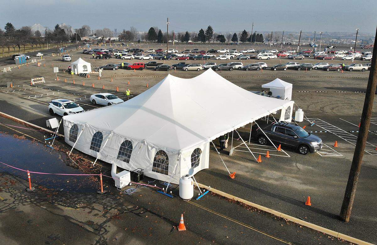 A cars pulls from the registration area towards the vaccination tent Tuesday morning at the mass drive-thru COVID-19 vaccination site as hundreds of other vehicles wait in a line snaking through the parking lot of the Benton County Fairgrounds in Kennewick. I