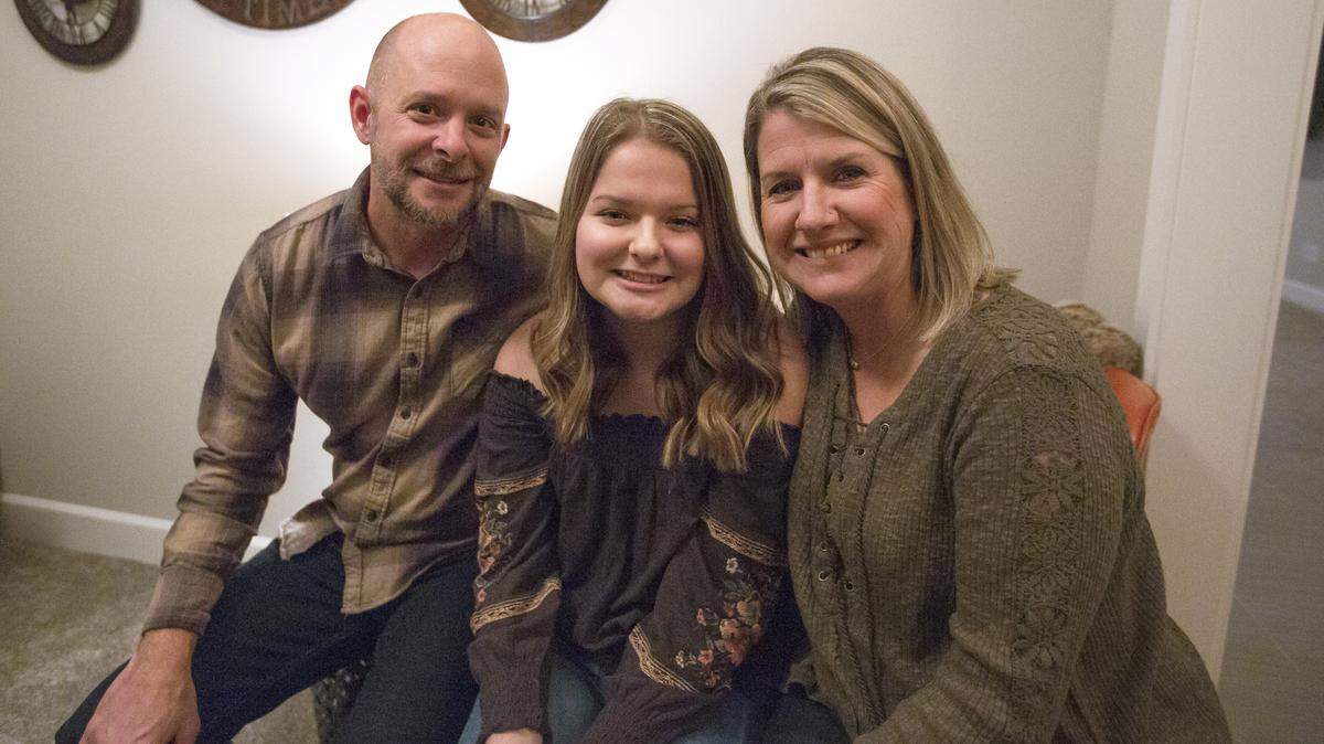 Kamiakin freshman Emily Larson, center, sits with her parents Scott, left, and Cindy. Last fall, the Tri-City gymnast developed meningitis and spent more than a month in the hospital.