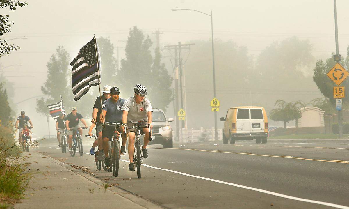 Bicyclists pedal their way through the smoky air on South Union Street to the 9-11 Memorial in Kennewick. They were Kennewick firefighters and family members commemorating the 19th anniversary of the terrorist attacks. An annual run held by the firefighters and police was canceled this year because of the coronavirus pandemic.
