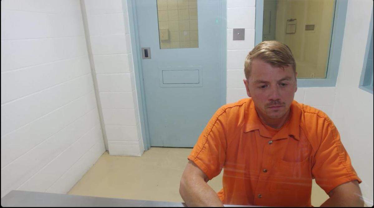 Joshua Riley, a Kennewick police detective facing possible domestic violence assault charges, appeared briefly from the Franklin County jail before being taken to the Benton County jail.