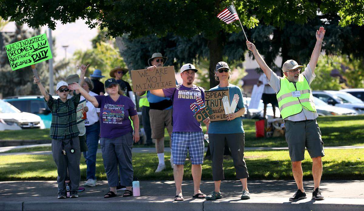 Protesters with Indivisible Tri-Cities stand on the sidewalk along George Washington Way near Richland’s John Dam Plaza to oppose the “One Big Beautiful Bill.”