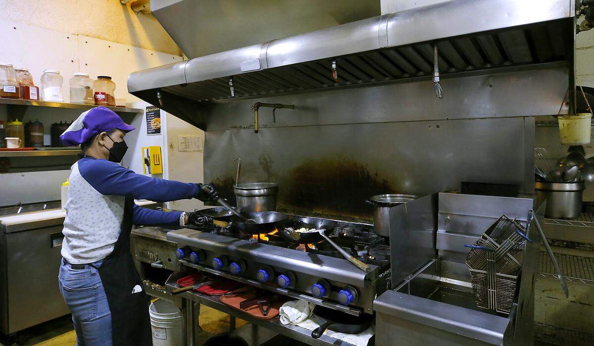 An employee at the Emerald of Siam cooks a lunch order Tuesday at the Thai restaurant and event venue in Richland's Uptown Shopping Center. 